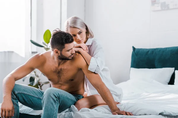 Atractiva pareja joven sentados en la cama juntos - foto de stock