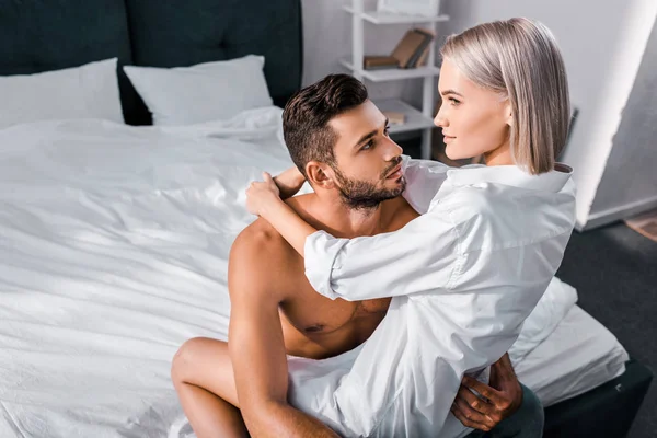 High angle view of beautiful young woman sitting on boyfriend in bedroom — Stock Photo