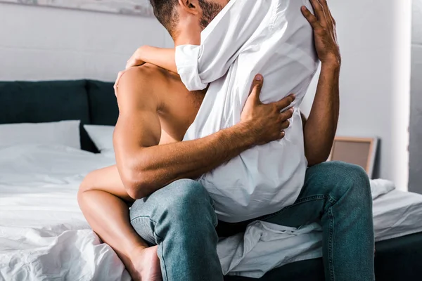 Cropped shot of young woman sitting on boyfriend in bedroom — Stock Photo