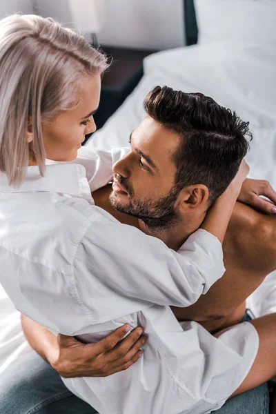 High angle view of attractive young woman sitting on boyfriend in bedroom — Stock Photo