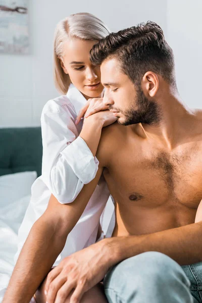 Attractive young woman leaning on her boyfriend from behind in bedroom — Stock Photo