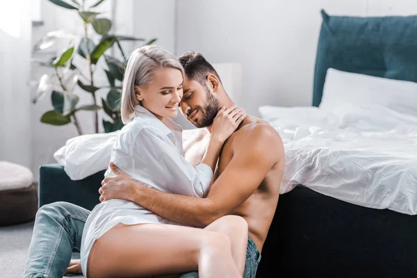 Mujer apasionada feliz sentado en su novio en el piso del dormitorio — Stock Photo