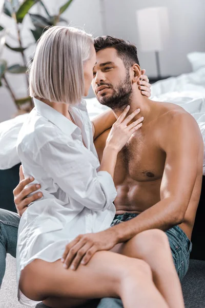 Attractive young woman sitting on her boyfriend on floor of bedroom — Stock Photo