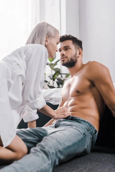 Passionate young woman undressing her boyfriend on floor of bedroom — Stock Photo