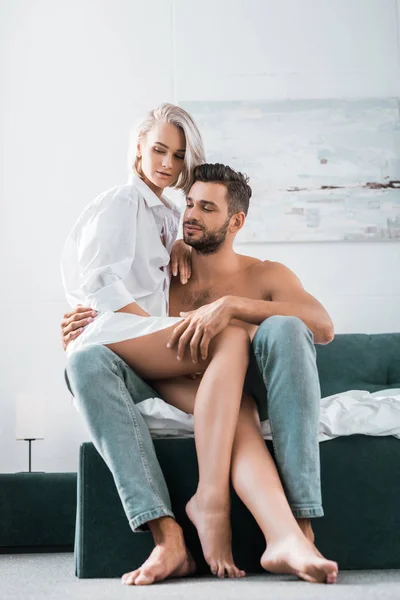 Atractiva pareja joven en sentarse en la cama juntos - foto de stock