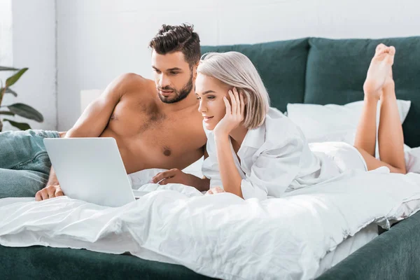 Belo jovem casal usando laptop juntos no quarto — Fotografia de Stock