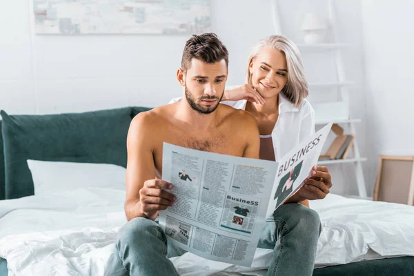 Schönes junges Paar liest gemeinsam Zeitung im Schlafzimmer — Stockfoto
