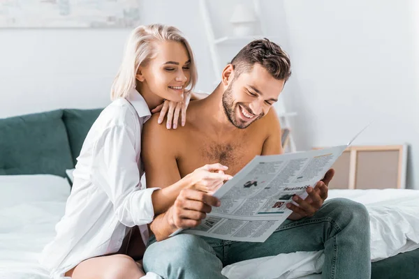 Feliz jovem casal ler jornal juntos no quarto — Fotografia de Stock