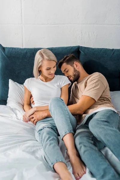 Atractiva pareja joven abrazándose juntos en el dormitorio - foto de stock