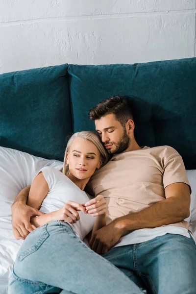 Junges Paar umarmt sich auf dem Bett, schöner Freund schläft in der Nähe der Freundin — Stockfoto