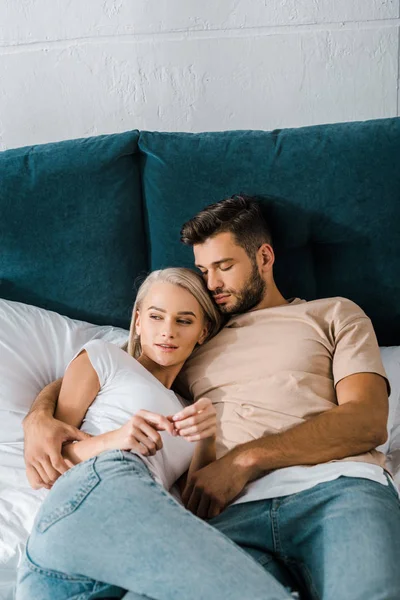 Pareja joven abrazándose en la cama, guapo novio durmiendo cerca de novia - foto de stock