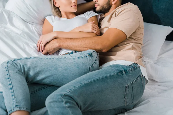 Imagem cortada de jovem casal abraçando na cama no quarto — Fotografia de Stock