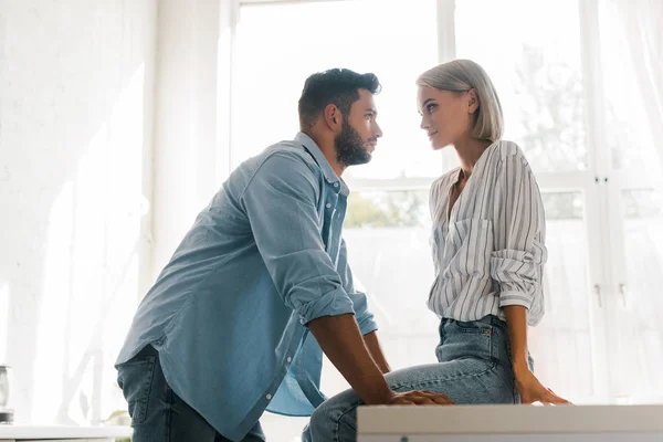 Seitenansicht eines jungen Paares, das sich in der Küche anschaut — Stockfoto