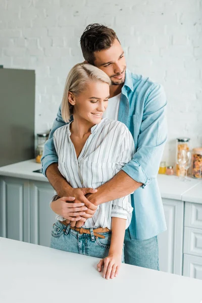 Sensual sonriente novio abrazando novia de vuelta en la cocina — Stock Photo