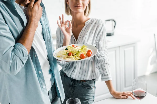 Cropped image of girlfriend showing okay gesture to salad in kitchen — Stock Photo