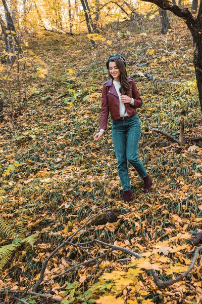 Щаслива стильна жінка в шкіряній куртці, що йде в автономному лісі — стокове фото