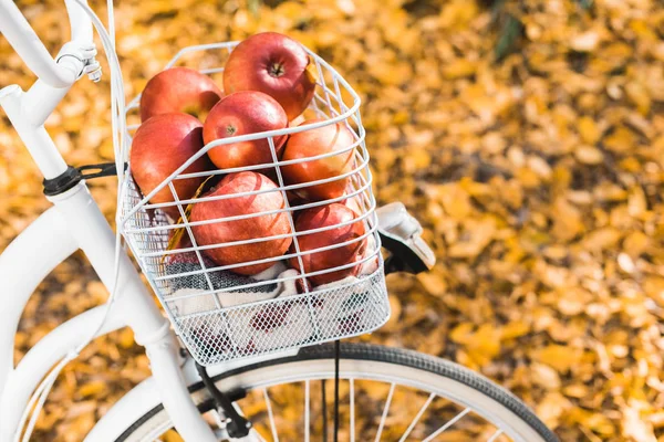 Enfoque selectivo de la bicicleta con cesta llena de deliciosas manzanas rojas al aire libre - foto de stock