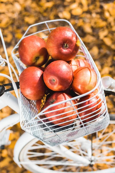 Gros plan du vélo avec panier plein de délicieuses pommes rouges à l'extérieur — Photo de stock