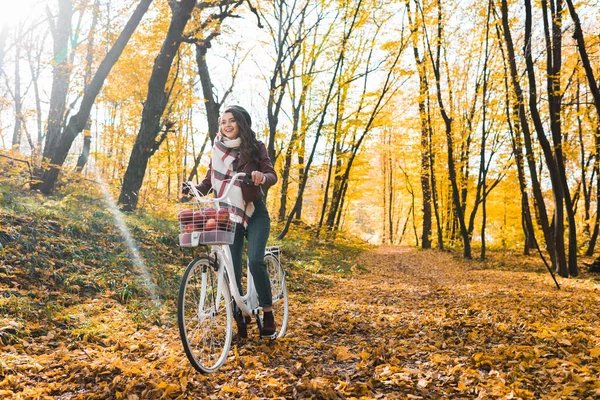 Foyer sélectif de fille heureuse en veste en cuir et béret équitation sur vélo dans la forêt jaune automnale — Photo de stock