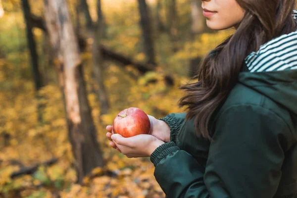 Cropped image of young woman holding red apple outdoors — Stock Photo