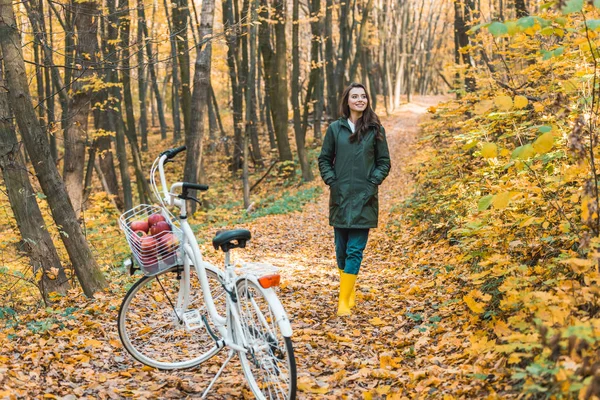 Дівчина в жовтих гумових чоботях, що йдуть біля велосипеда в автономному лісі — стокове фото