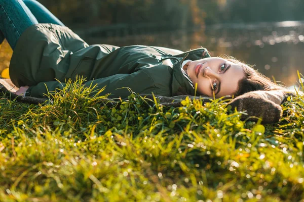 Selective focus of attractive woman in laying on blanket and looking at camera outdoors — Stock Photo