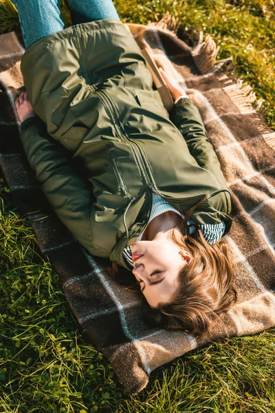 Высокий угол обзора молодой женщины, спящей на одеяле на открытом воздухе — стоковое фото