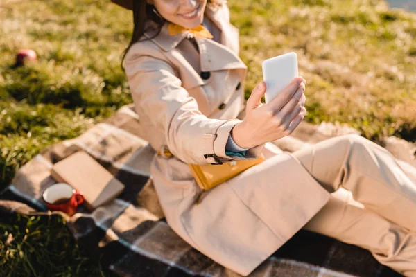 Vue partielle de la femme élégante dans le chapeau prendre selfie sur smartphone à l'extérieur — Photo de stock