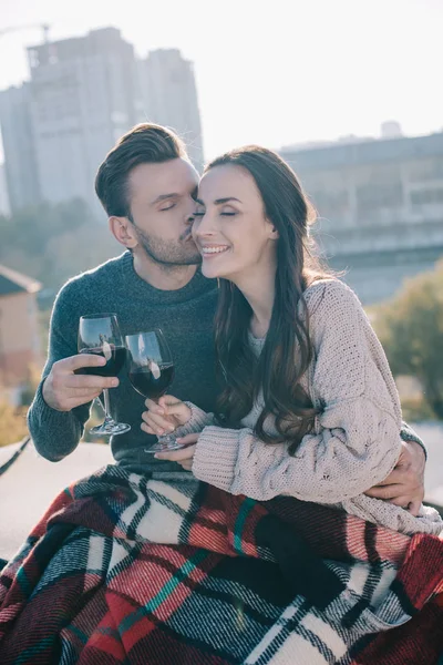 Schönes junges Paar in karierten und klirrenden Gläsern Rotwein auf dem Dach — Stockfoto