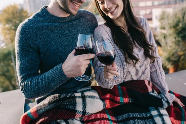 Schnappschuss eines schönen jungen Paares, das sich in Karo hüllt und auf dem Dach Rotwein trinkt — Stockfoto