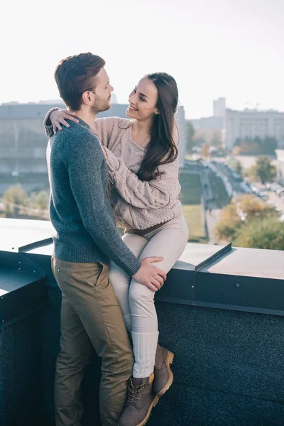 Sonriente joven pareja abrazándose y mirándose en la azotea - foto de stock