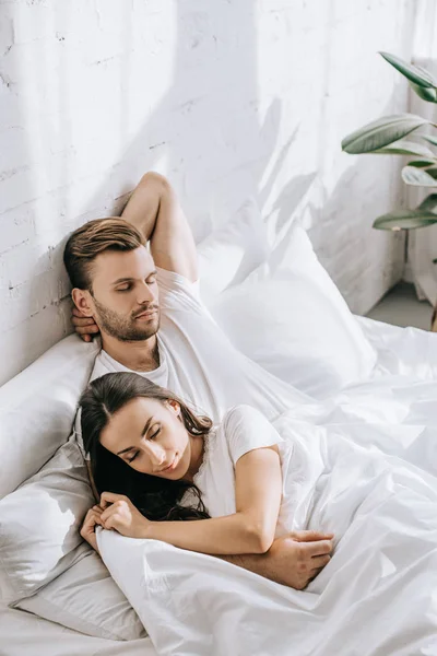 Hermosa pareja joven durmiendo en la cama por la mañana - foto de stock