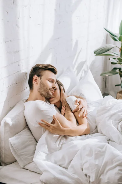 Belo jovem casal abraçando na cama de manhã — Fotografia de Stock