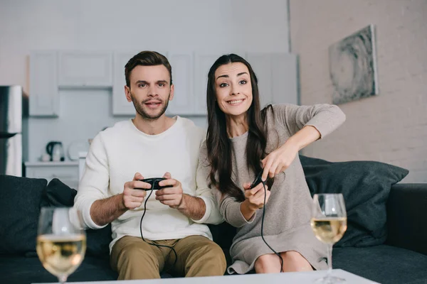 Feliz joven pareja jugando retro video juego en sofá en casa - foto de stock