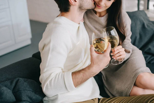 Recortado disparo de joven pareja bebiendo vino y coqueteando en sofá en casa - foto de stock