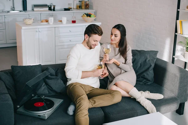 High angle view of happy young couple listening music with vinyl record player and drinking wine at home — Stock Photo