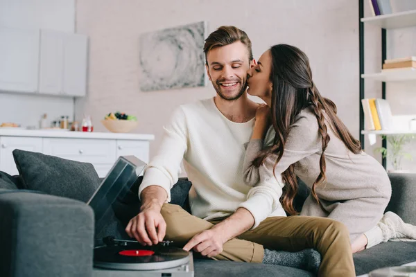 Happy young couple listening music with vinyl record player and cuddling at home — Stock Photo
