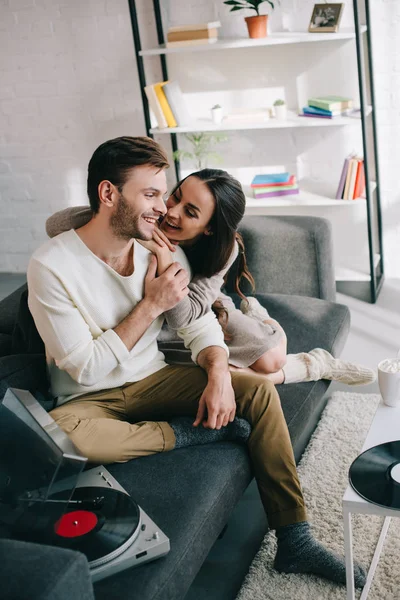 Schönes junges Paar hört Musik mit Plattenspieler und kuschelt zu Hause — Stockfoto