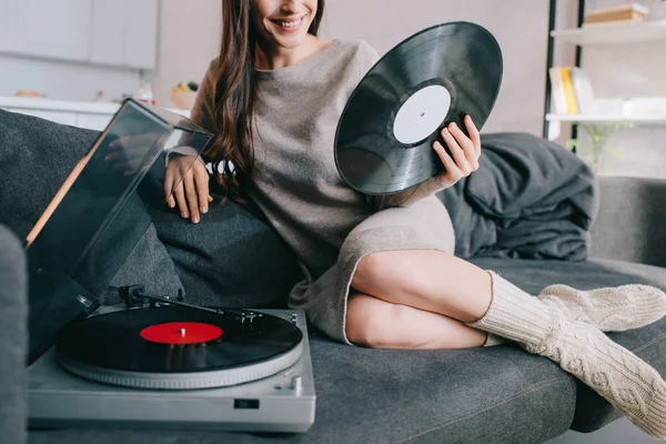 Cropped shot of young woman listening music with vinyl record player on couch at home — Stock Photo