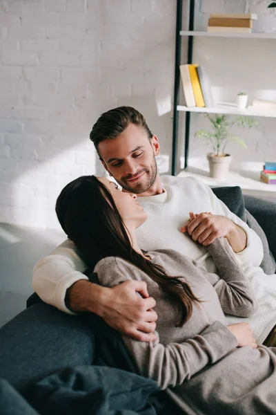 Красива молода пара розслабляється на дивані і тримає руки вдома — стокове фото