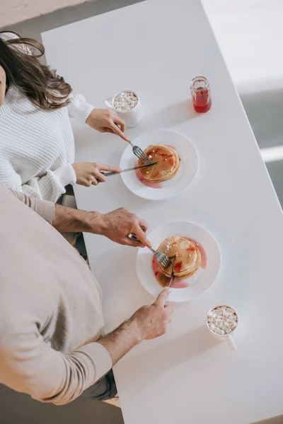 Vue grand angle du couple avec crêpes et cacao pour le petit déjeuner à la maison — Photo de stock