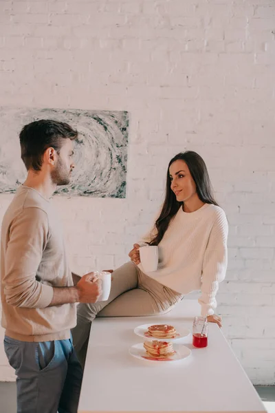 Glückliches junges Paar frühstückt zusammen und plaudert zu Hause — Stockfoto