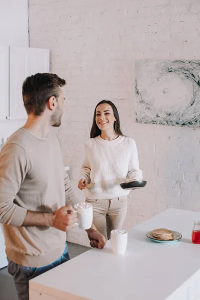 Hermosa pareja joven haciendo el desayuno juntos en casa - foto de stock