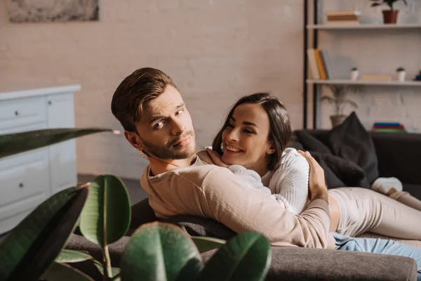 Happy romantic young couple flirting on couch at home — Stock Photo