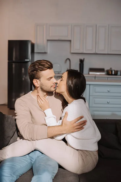 Romantic young couple kissing on couch at home — Stock Photo