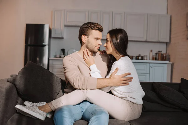 Romântico jovem casal abraçando no sofá em casa — Fotografia de Stock