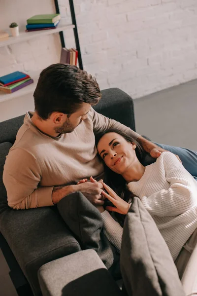 Високий кут зору щасливої молодої пари розслабляється на дивані разом вдома — стокове фото