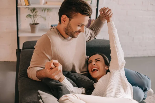 Belo jovem casal jogando no sofá em casa — Fotografia de Stock