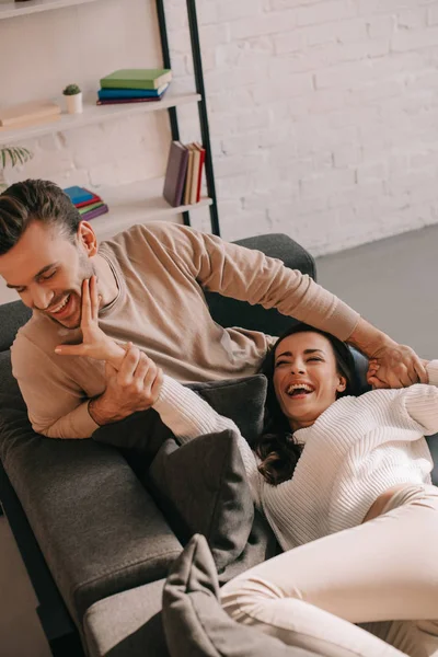 Belo jovem casal jogando no sofá em casa — Fotografia de Stock