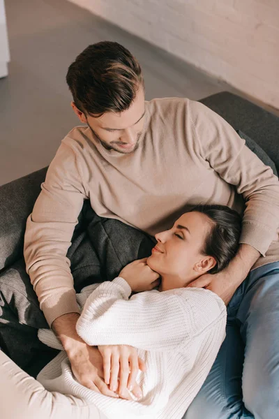 Blick aus der Vogelperspektive auf ein glückliches junges Paar, das es sich zu Hause auf der Couch gemütlich macht — Stockfoto